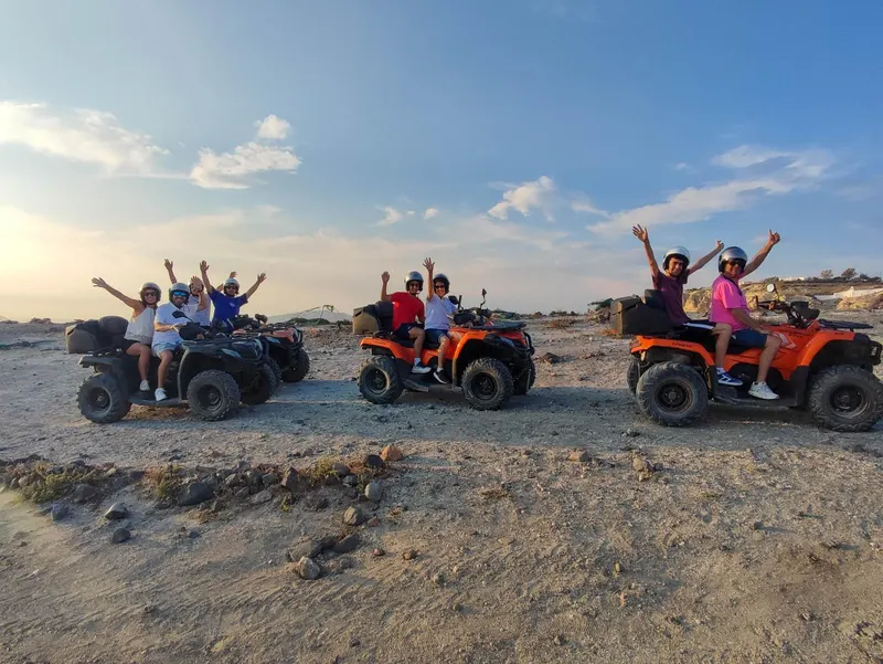 ATV tour group celebrating on a dirt road overlooking the Santorini coast