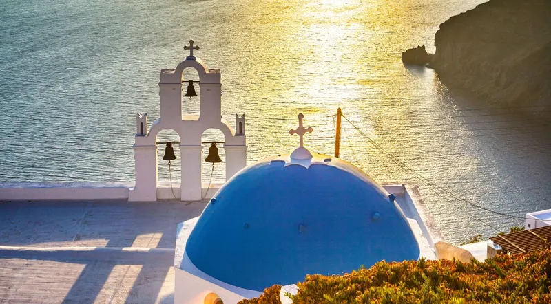 Blue-domed church above the caldera at sunset, Santorini