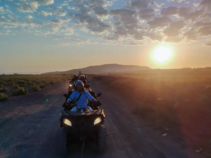 Rider on a quad on an open Santorini road at sunset