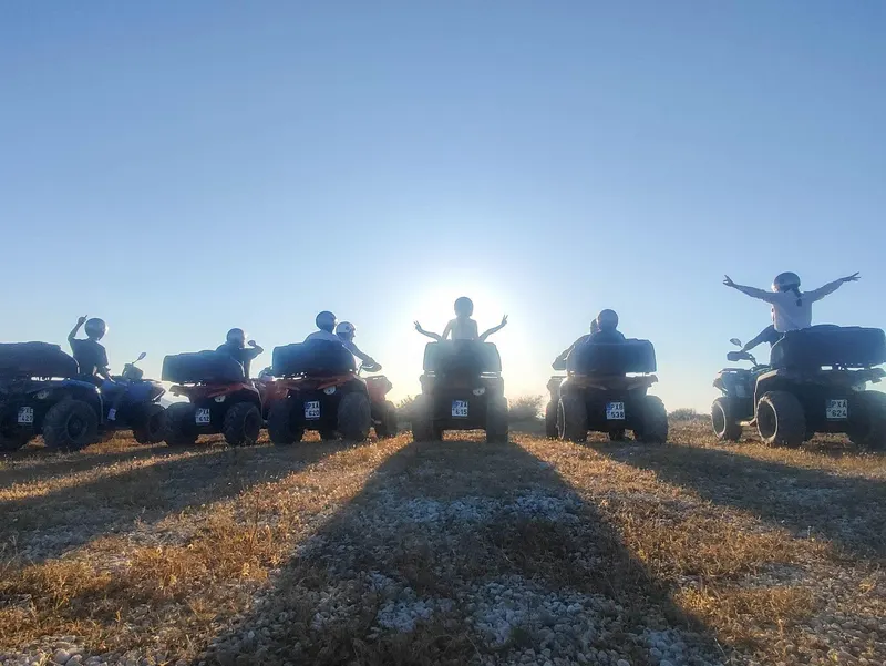ATV quads silhouetted in a line against the Santorini sunset