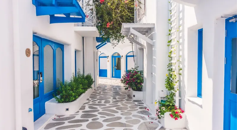 Whitewashed Santorini village alley with blue doors and bougainvillea
